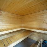 Holzsauna mit mehreren Sitzbänken und einem Eimer.