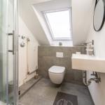 Dusche, Toilette und Waschbecken unter Dachschräge mit Dachfenster.