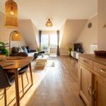 Wohn- und Essbereich mit Holzboden, Sitzgruppe, TV und Tisch mit Stühlen.