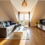 Wohnzimmer mit Sofa, Couchtisch und Fernseher. Holzboden und Dachschräge.