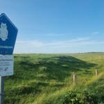 Nationalpark-Zeichen weist auf Schutzzone hin. Grünland und Himmel im Hintergrund.