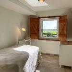 Bedroom with bed, window, and cabinet. Outside is a green landscape visible.