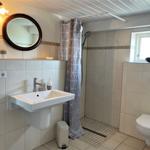 Bathroom with shower, sink, and toilet. Window, mirror, and shower curtain visible.