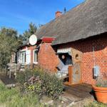 Red brick house with thatched roof, garden area with sun lounger and table