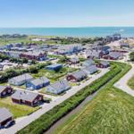Aerial view of holiday homes by the sea with harbor and ship.
