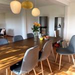Dining area with wooden table, gray chairs, and three pendant lights.