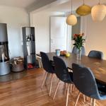 Dining room with table, chairs, fireplace, and pendant lamps.