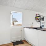 Küche mit weißer Arbeitsplatte, schwarzer Spüle und Fenster zur Terrasse.