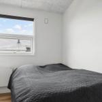 Schlafzimmer mit Bett, Fenster und Wandheizung.