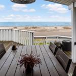 Terrasse mit Tisch und Stühlen, Blick auf Strand und Meer.