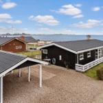 Schwarzes Holzhaus mit weißem Geländer und Terrasse direkt am Wasser.