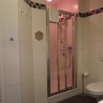 Badezimmer mit Dusche, Toilette und Handtuchheizung.