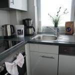 Küche mit Spüle, Kaffeemaschine und Kochfeld.