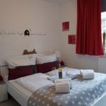 Schlafzimmer mit Bett, roten Vorhängen und Wanddekoration.