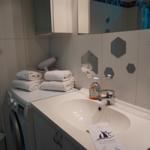 Badezimmer mit Waschmaschine, Spiegel und Handtüchern