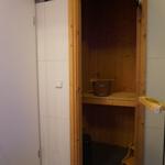 Sauna mit Holzbank und Eimer, getrennt durch Glaswand.