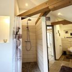 Dusche mit Duschvorhang und Holzbalken an der Decke.