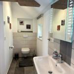 Badezimmer mit Waschbecken, Spiegel und Toilette unter Holzbalken.