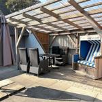 Terrasse mit Pavillon, Tisch, Stühlen und Strandkorb.