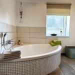 Bad mit Whirlpool, Fenster, Handtuch und Waschmaschinenkorb.