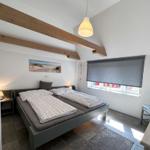 Schlafzimmer mit Doppelbett, Holzbalken und Fenster mit Rollladen.