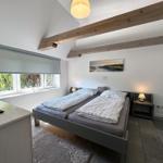 Schlafzimmer mit Doppelbett, Fenster und Holzbalken an der Decke.