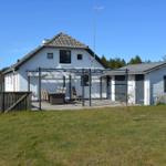 Wohnhaus mit Terrasse und Garten. Außentisch mit Stühlen. Hintergrund: Wald und klarer Himmel.