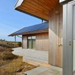 Moderne Holzhütte mit Solarpaneelen und Terrasse im Freien