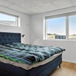 Schlafzimmer mit Bett, Fenstern und Holzboden.