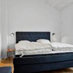 Schlafzimmer mit Doppelbett, dunklem Kopfteil und Fenster