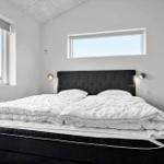 Schlafzimmer mit großem Bett, zwei Fenstern und Wandlampen.