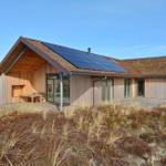 Moderne Holzhütte mit Solarpaneelen und großzügigen Glasflächen im Freien.