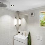 Badezimmer mit Dusche, Waschbecken und Fenster zum Garten.