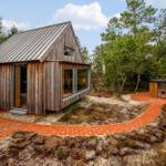 Holzhütte mit Glasfront und rotem Ziegelweg im Wald
