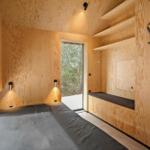 Schlafzimmer mit Holzwand, Bett und Fenster zur Außenseite.