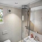 Badezimmer mit Dusche, Waschbecken und Fenster mit Blick auf Grün.