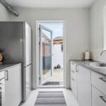 Küche mit Kühlschrank, Spüle und Tür zum Hof