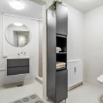 Badezimmer mit Toilette, Waschbecken und hohem Schrank.