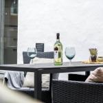 Terrasse mit Tisch, Stühlen, Weinflasche und Gläsern.