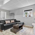 Wohnzimmer mit grauem Sofa, Holztisch und Wandbild