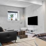 Wohnzimmer mit Sofa, Fernseher und Fenster. Holzboden und Wandgestaltung.