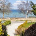 Gehweg führt zum Strand mit Blick aufs Wasser und Bäume.