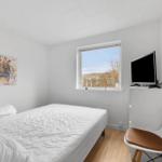 Schlafzimmer mit Bett, Fernseher und Fenster