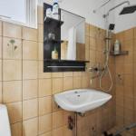 Badezimmer mit Dusche, Waschbecken und Toilette. Wandfliesen mit Blumenmotiv.