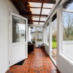 Terrasse mit roten Fliesen und Glasfronten führt zu einem Sitzbereich.