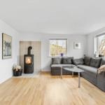 Wohnzimmer mit Kamin, grauem Sofa und Holzboden.