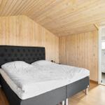 Schlafzimmer mit Holzwand und Bett. Nebenraum mit Toilette.