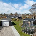 Modernes Haus mit Garage, Gewächshaus und Garten. Blick auf Wohnhaus und Umgebung.
