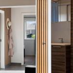 Haus mit modernem Badezimmer und Eingangsbereich mit Holzverkleidung und Kleidungsständer.