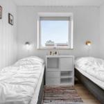 Two beds with white bedding are in a room with white walls and a window.